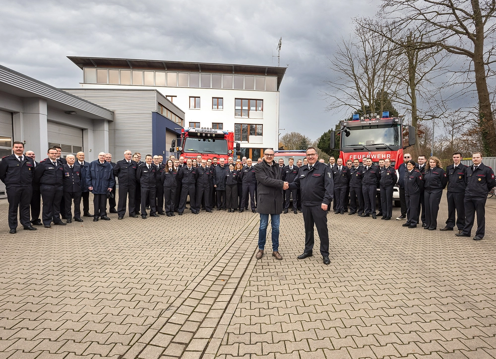 Gruppenbild: Freiwillige Feuerwehr Lemgo bei der Übergabe der neuen Fahrzeuge, die im Hintergrund stehen. Im Vordergrund: Bürgermeister Markus Baier (vorne links) und Lars-Uwe Brede, Leiter der Feuerwehr Lemgo (vorne rechts)