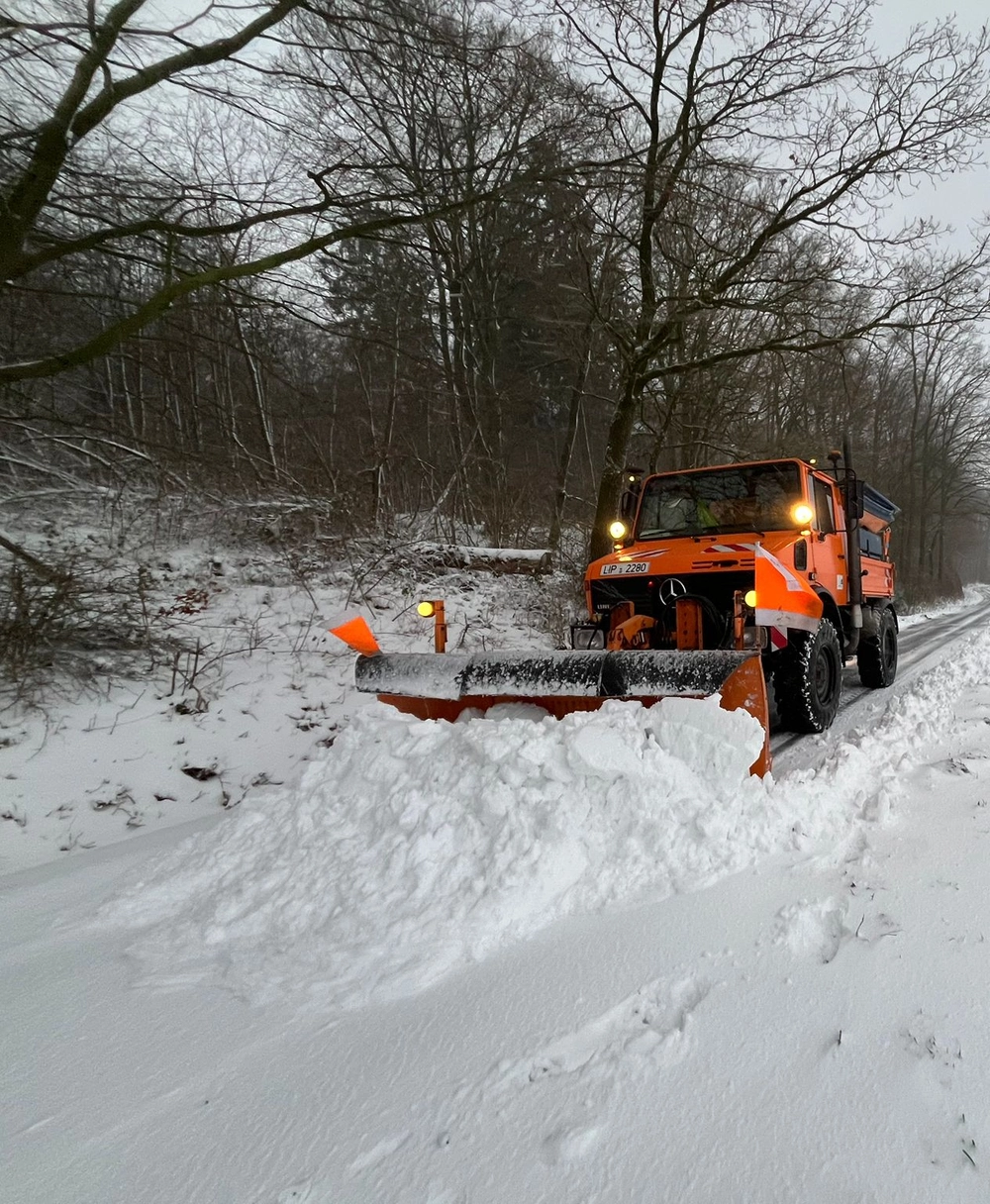 Ein Räumfahrzeug schiebt eine Menge Schnee vor sich her.