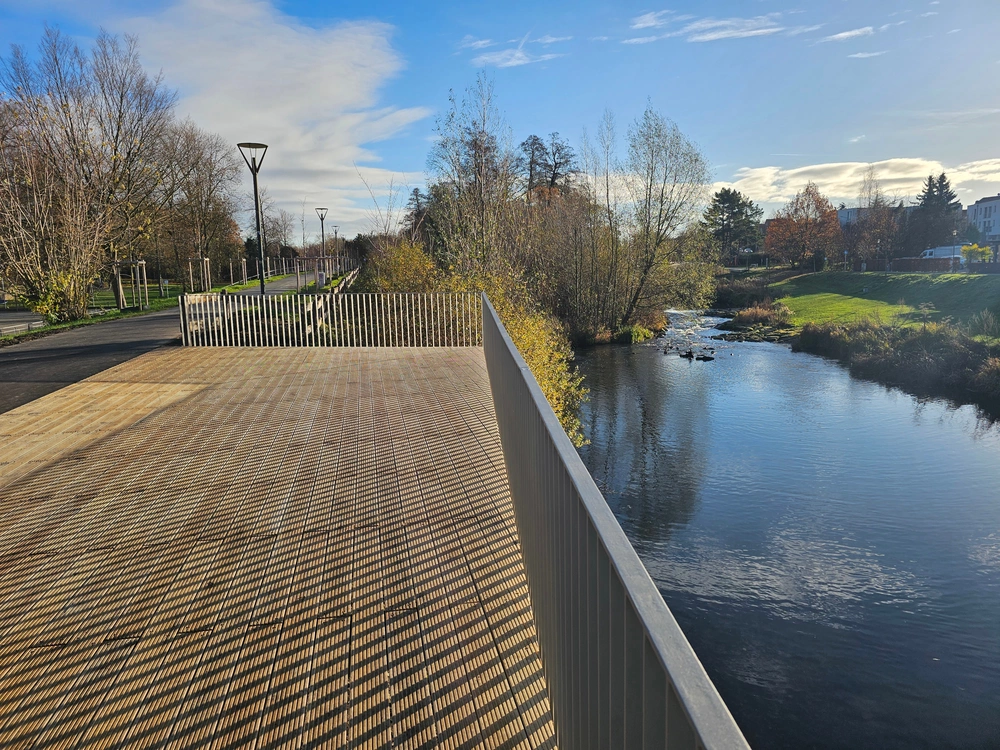 Blick auf das Holzdeck der Bega-Terrasse mit dem Lindenwall zur linken Hand und der Bega und dem Auen-Park zu rechten Hand.