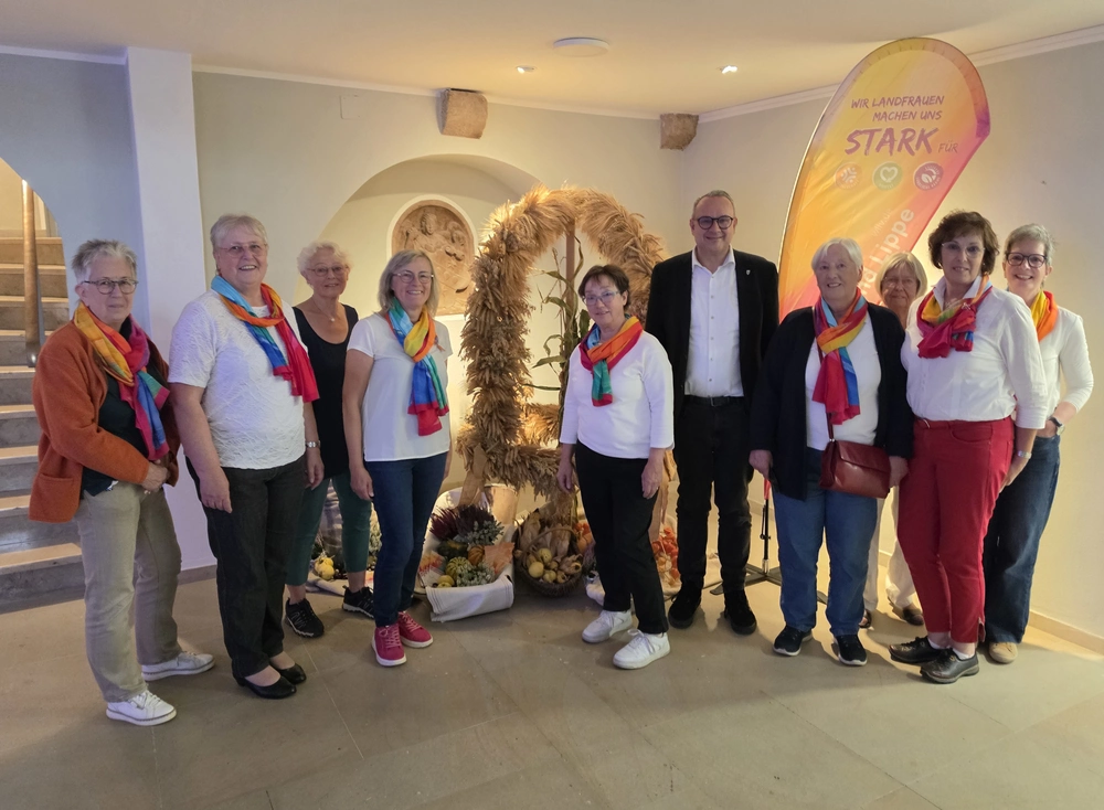 Ein Gruppe von Frauen und der Bürgermeister stehen vor einer großen Erntekrone.