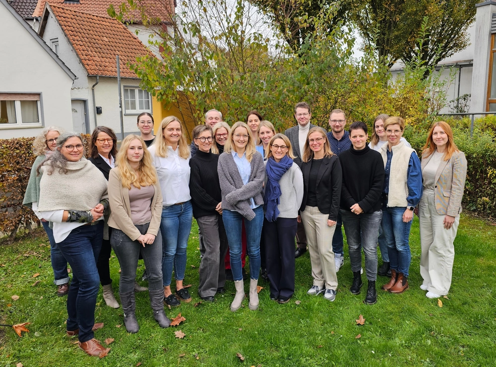 Eine Gruppe von Menschen steht auf einem Stück Rasen für das Foto aufgestellt.