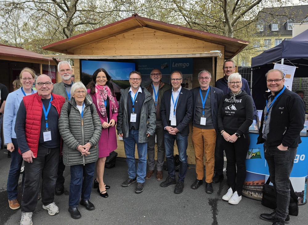 Eine Holzhütte mit Lemgo-Dekorationen, davor eine Gruppe von Menschen.