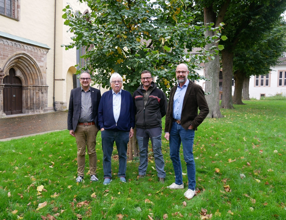 Vier Personen vor einem jungen Baum.