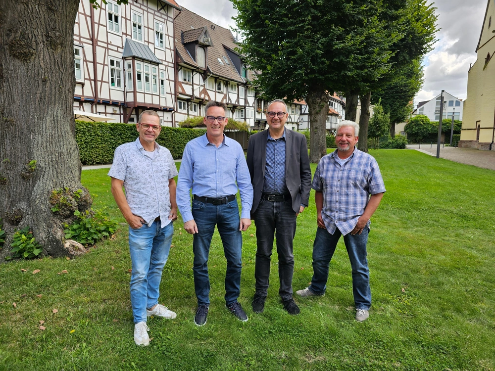 Vier Männer stehen nebeneinander im Freien.