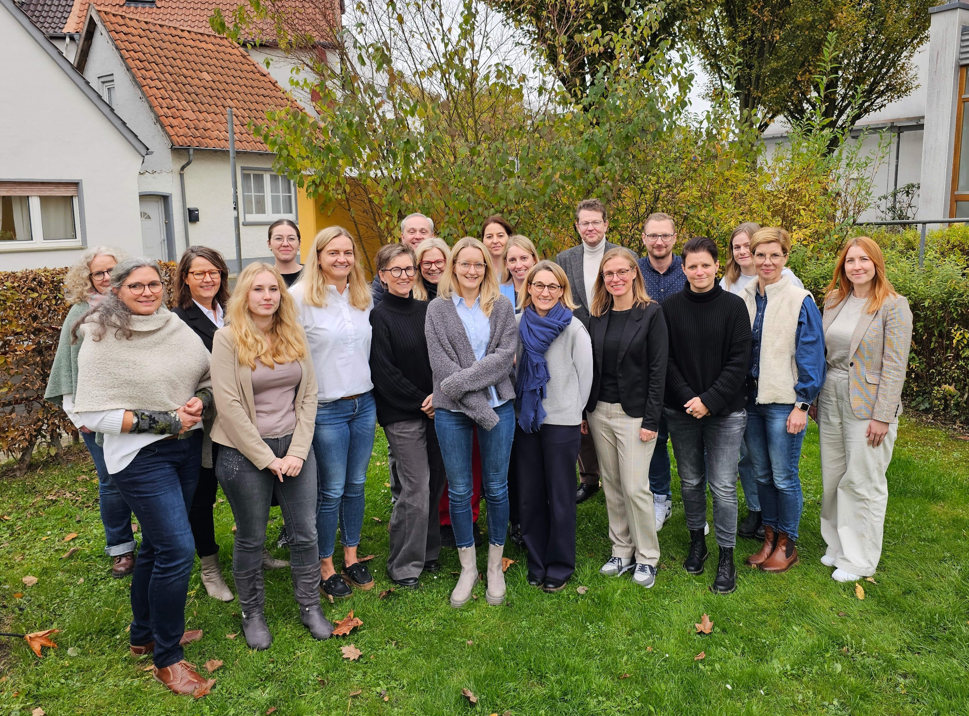 Eine Gruppe von Menschen steht auf einem Stück Rasen für das Foto aufgestellt.