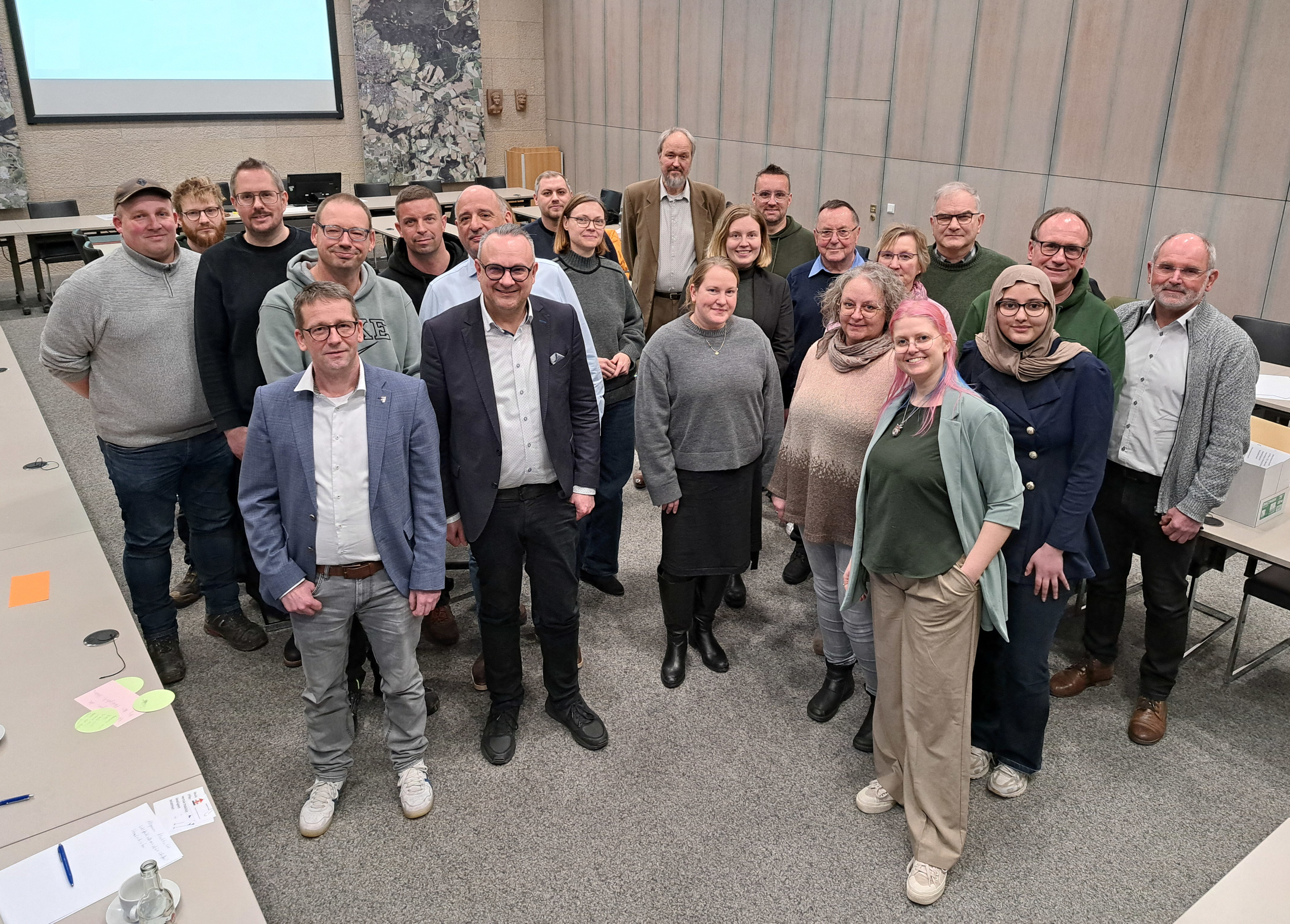 Eine Gruppe von Menschen steht im großen Sitzungssaal des Rathauses.