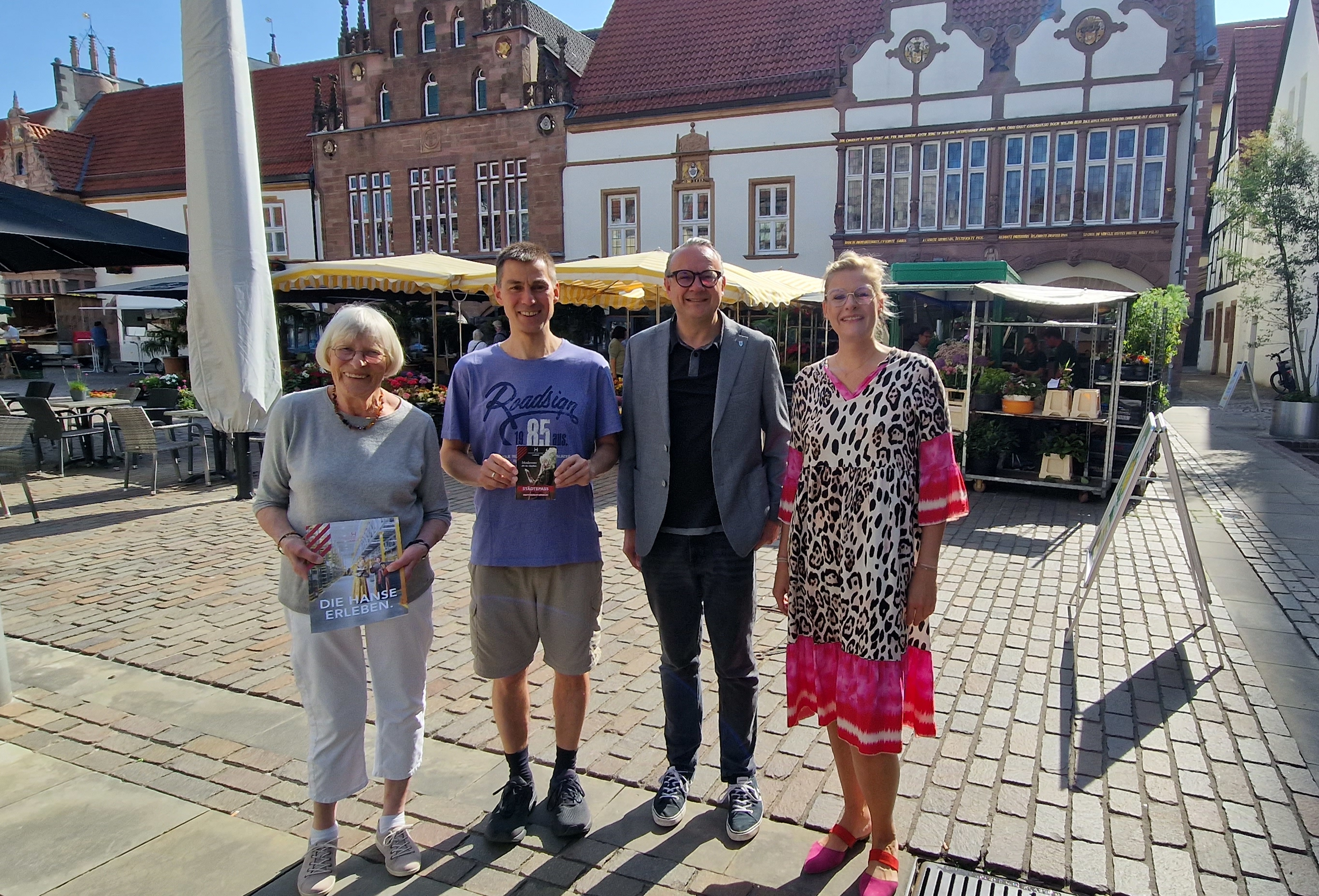 Vier Personen stehen auf dem Marktplatz.