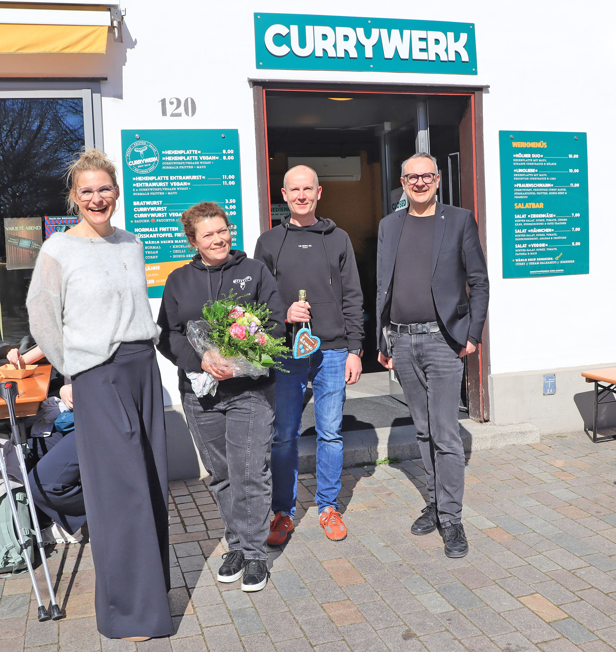 Vier Personen vor einem Ladengeschäft mit der Überschrift "Currywerk".